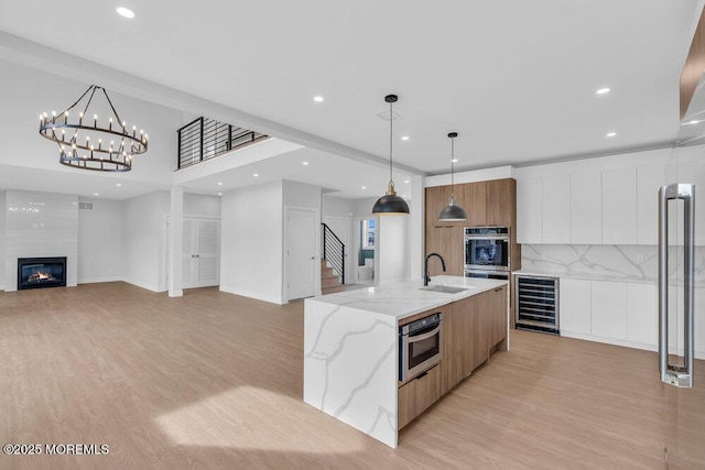 kitchen featuring light wood-style flooring, white cabinetry, beverage cooler, and modern cabinets
