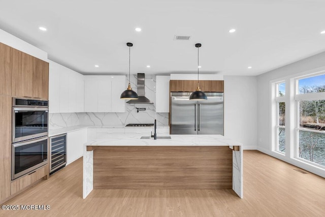 kitchen with visible vents, modern cabinets, wall chimney range hood, wine cooler, and stainless steel appliances
