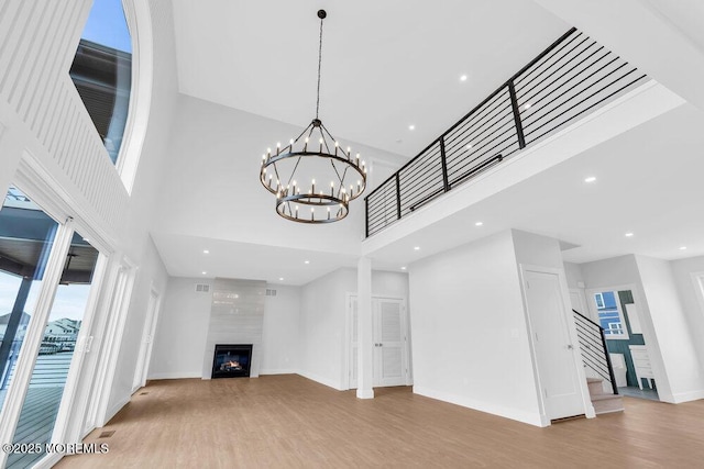 unfurnished living room with a large fireplace, recessed lighting, stairway, wood finished floors, and baseboards