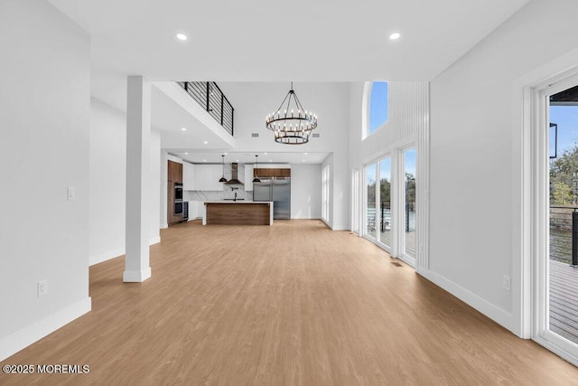 unfurnished living room with light wood-style flooring, an inviting chandelier, and a healthy amount of sunlight
