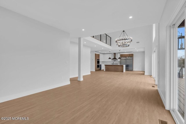 unfurnished living room with baseboards, an inviting chandelier, recessed lighting, visible vents, and light wood finished floors