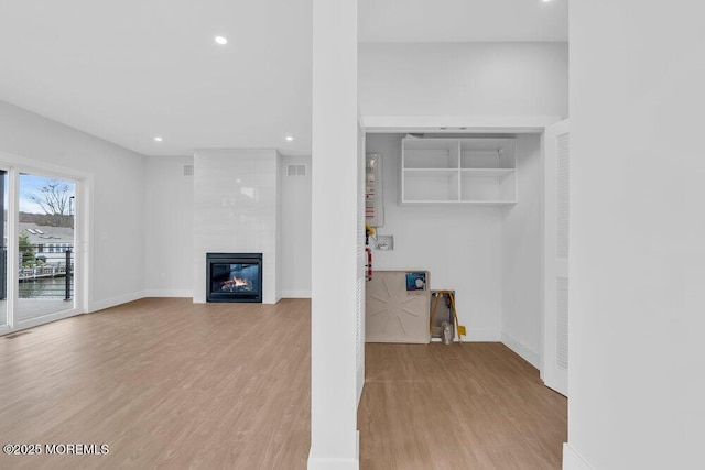 unfurnished living room with recessed lighting, baseboards, light wood-type flooring, and a tile fireplace