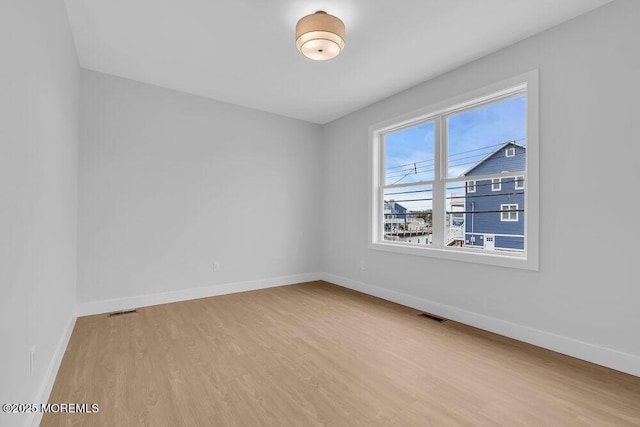 empty room featuring light wood-style flooring, baseboards, and visible vents