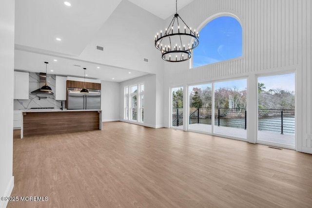 unfurnished living room with light wood-style flooring, an inviting chandelier, visible vents, and recessed lighting