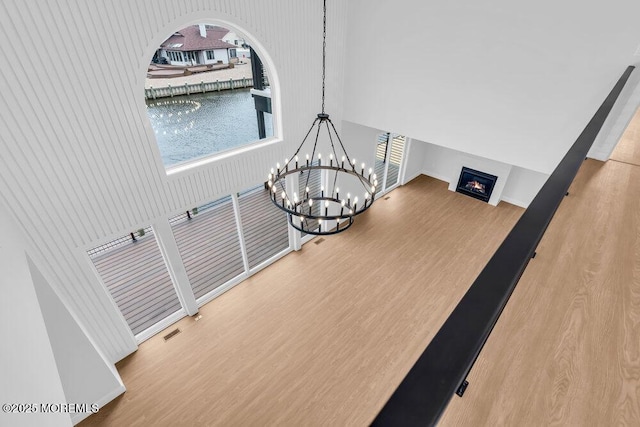 interior space with visible vents, wood finished floors, an inviting chandelier, and a warm lit fireplace