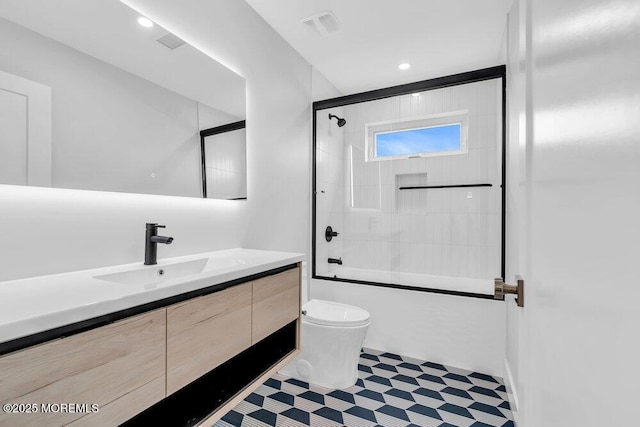 bathroom featuring vanity, visible vents, toilet, and enclosed tub / shower combo