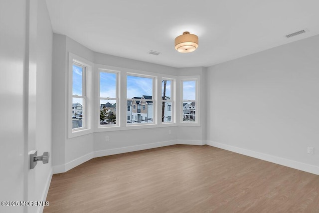 empty room featuring visible vents, baseboards, and wood finished floors