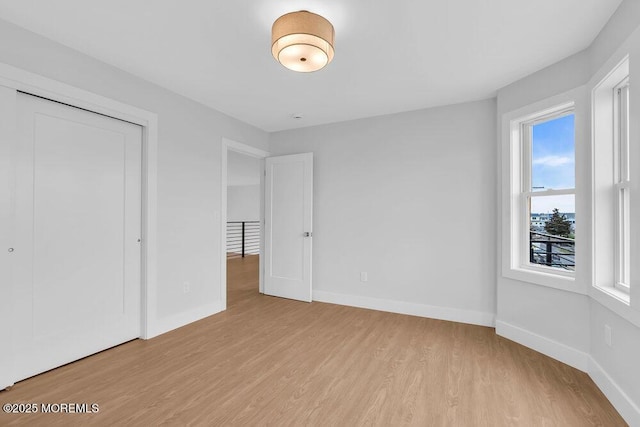 unfurnished bedroom with a closet, baseboards, and wood finished floors