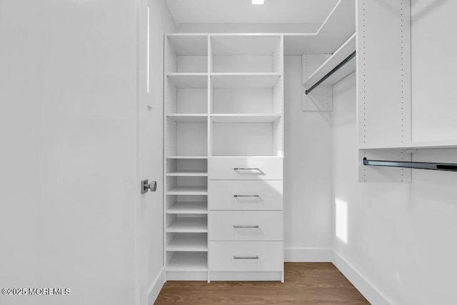 walk in closet with wood finished floors