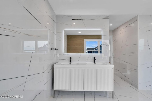bathroom featuring double vanity, a sink, and tile walls