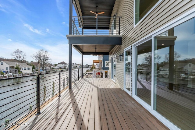 wooden terrace featuring a water view, a ceiling fan, and a residential view