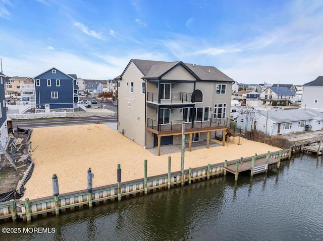 back of property with a water view, a residential view, a patio, and a balcony
