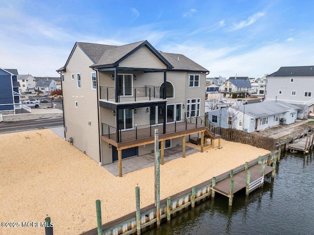rear view of property with a water view, a residential view, and a balcony