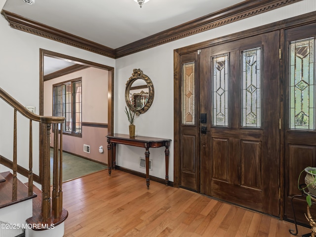entrance foyer featuring crown molding, light wood-type flooring, stairs, and visible vents