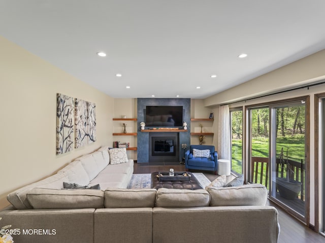 living area with a large fireplace, recessed lighting, and dark wood-type flooring