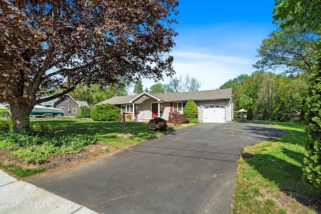 ranch-style home featuring an attached garage, a front lawn, and aphalt driveway