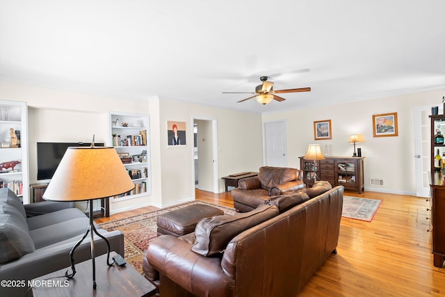 living room featuring a ceiling fan, visible vents, built in features, and light wood-type flooring