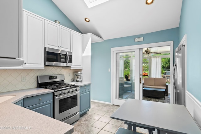 kitchen featuring vaulted ceiling with skylight, tasteful backsplash, light countertops, stainless steel appliances, and white cabinetry