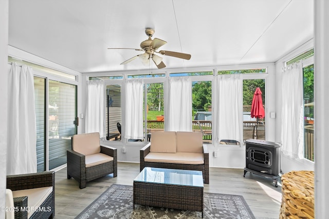sunroom featuring wood finished floors and a wood stove
