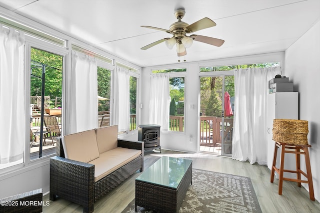 sunroom with a wood stove and wood finished floors