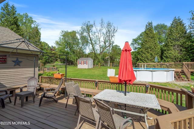 wooden terrace with outdoor dining area, an outdoor structure, an outdoor pool, and a storage unit