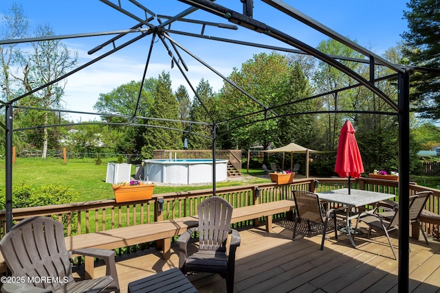 wooden deck with fence, outdoor dining space, a yard, and an outdoor pool