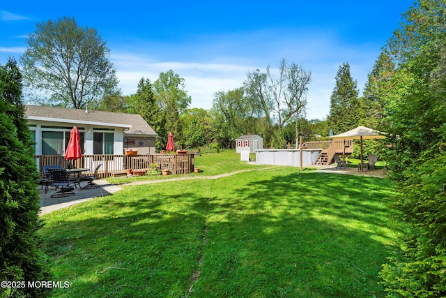 view of yard with a storage shed, an outdoor structure, a deck, and a patio