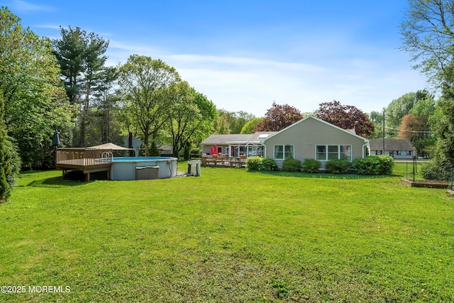 rear view of house featuring a yard, a wooden deck, and an outdoor pool