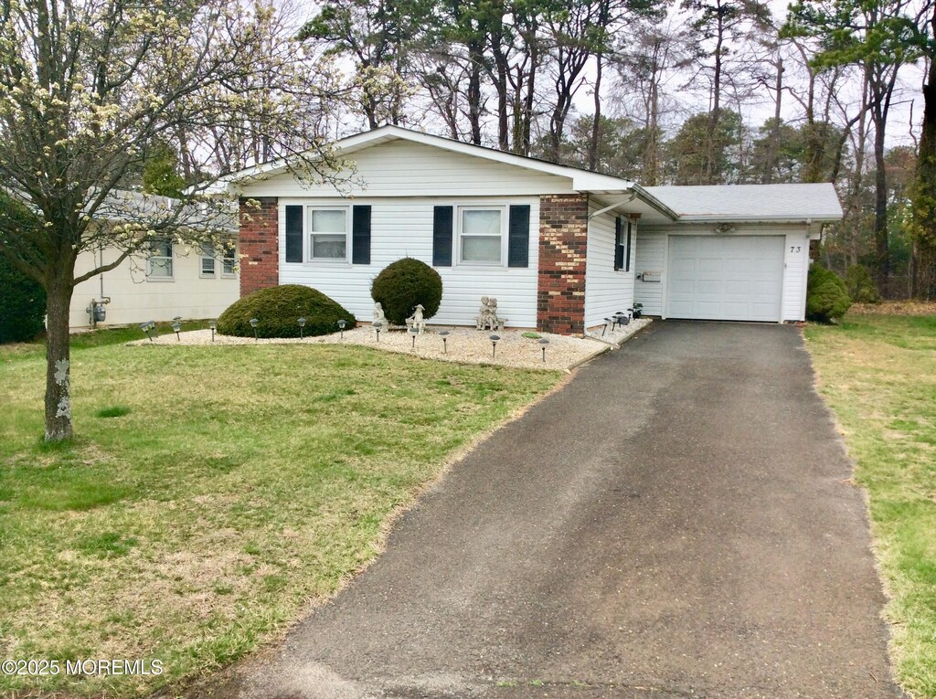 ranch-style home featuring aphalt driveway, a garage, a front lawn, and brick siding