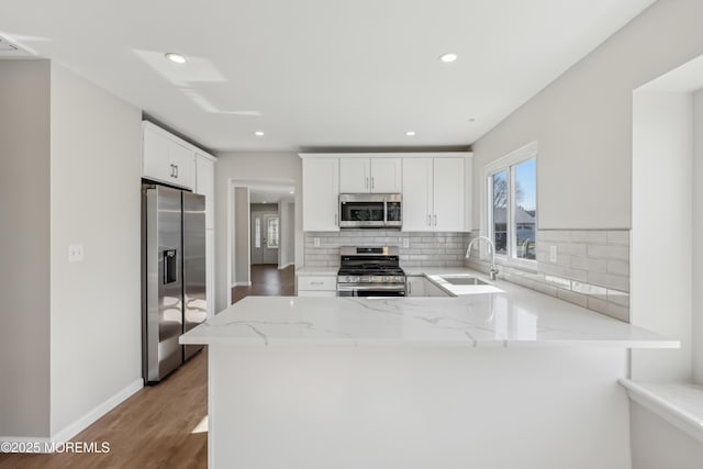 9 Weybridge Pl, Manchester, NJ 08759 - kitchen with appliances with stainless steel finishes, a sink, light stone countertops, tasteful backsplash, and a peninsula