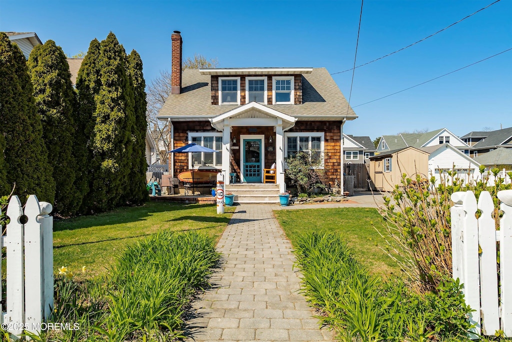 bungalow with a front yard, a chimney, fence, and roof with shingles