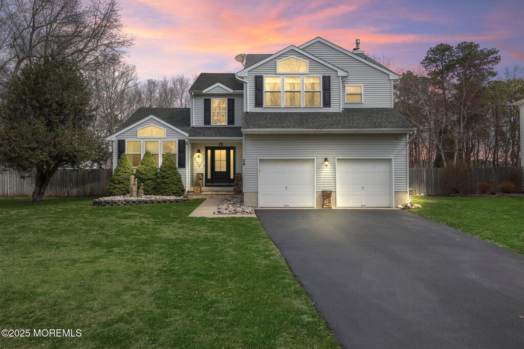traditional-style house featuring driveway, a garage, fence, and a yard