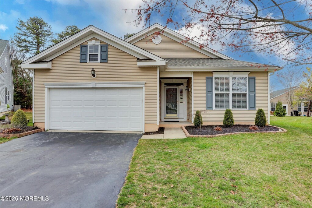 view of front facade featuring aphalt driveway, a garage, a shingled roof, and a front yard