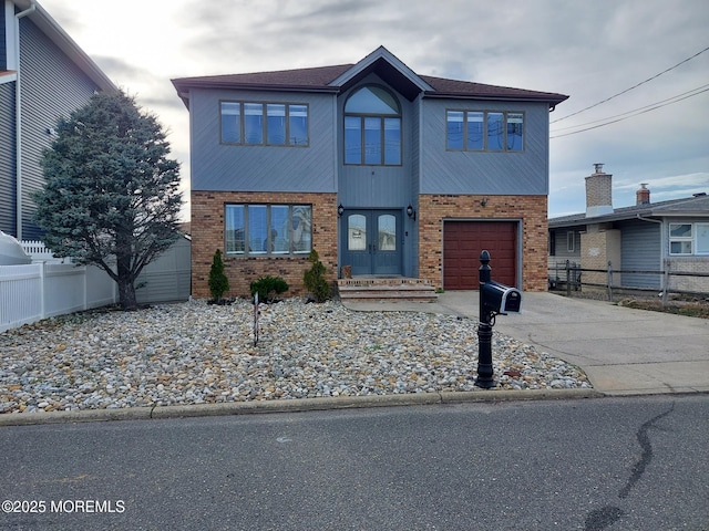 view of front of property with an attached garage, fence, french doors, and concrete driveway