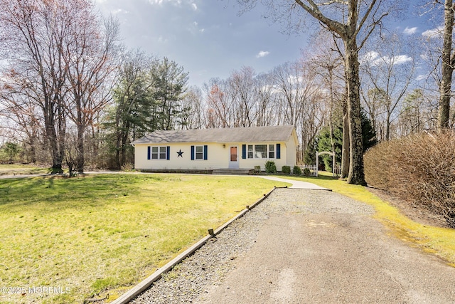 ranch-style home featuring a front lawn and gravel driveway