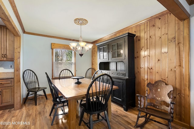 dining space featuring baseboards, crown molding, a chandelier, and light wood-type flooring