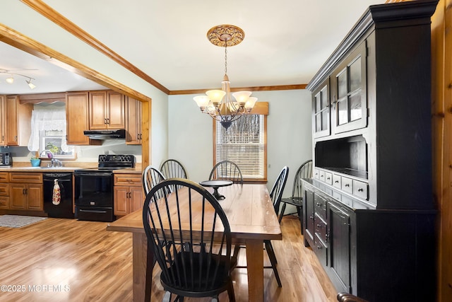kitchen with crown molding, light countertops, a chandelier, under cabinet range hood, and black appliances