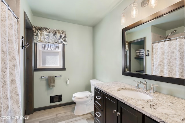 full bath featuring toilet, vanity, wood finished floors, baseboards, and visible vents