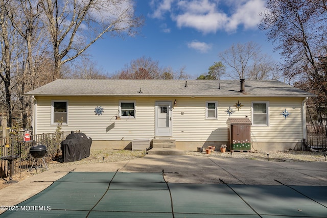 rear view of property featuring a patio area, entry steps, fence, and a covered pool