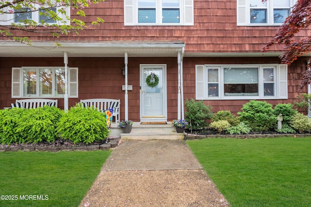 doorway to property featuring covered porch and a lawn