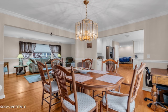 dining room featuring ornamental molding, a notable chandelier, and light wood-style floors