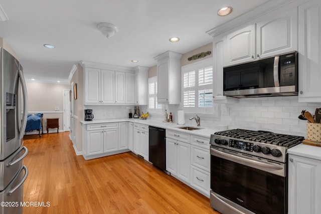 kitchen with a sink, decorative backsplash, light countertops, white cabinets, and appliances with stainless steel finishes