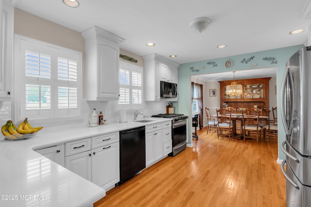 kitchen featuring a sink, stainless steel appliances, white cabinetry, light wood-style floors, and recessed lighting