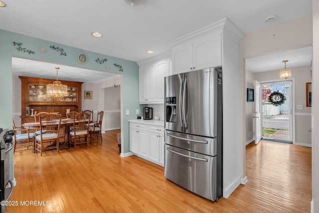 kitchen with stainless steel fridge, a chandelier, white cabinets, light wood-type flooring, and recessed lighting