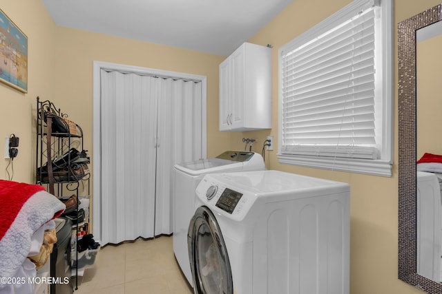 washroom with cabinet space, washing machine and clothes dryer, light tile patterned flooring, and a healthy amount of sunlight