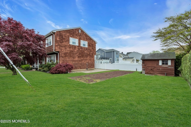 rear view of house with a storage unit, fence, an outdoor structure, and a lawn