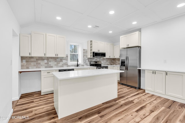 kitchen featuring light wood finished floors, a sink, appliances with stainless steel finishes, and tasteful backsplash