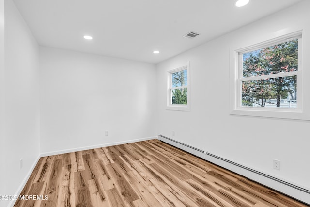 empty room with a baseboard radiator, recessed lighting, visible vents, and light wood-type flooring