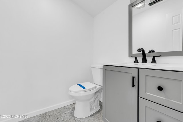 half bathroom featuring baseboards, vanity, and toilet