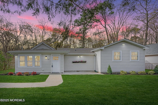 view of front facade with a shingled roof and a front lawn